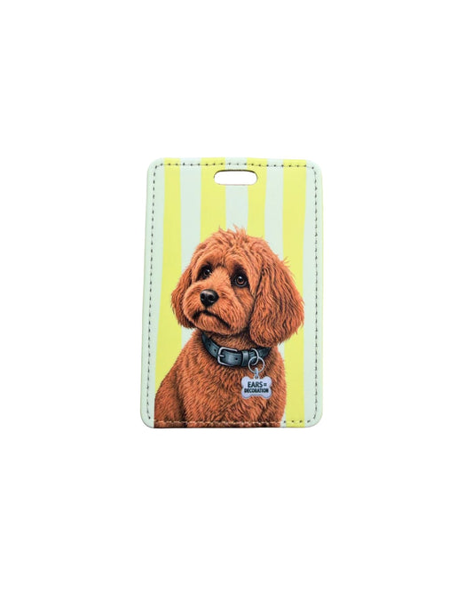 Cavapoo luggage tag; Fun faux leather luggage tag with an apricot curly-haired Cavapoo wearing an Ears Equal Decoration charm, vertical yellow and white stripes, white background.