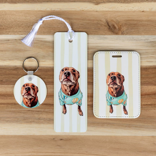 Custom pet essentials set: photo keychain, bookmark, and luggage tag featuring a stylized illustrated chocolate lab in a teal shirt, displayed on a wood background 