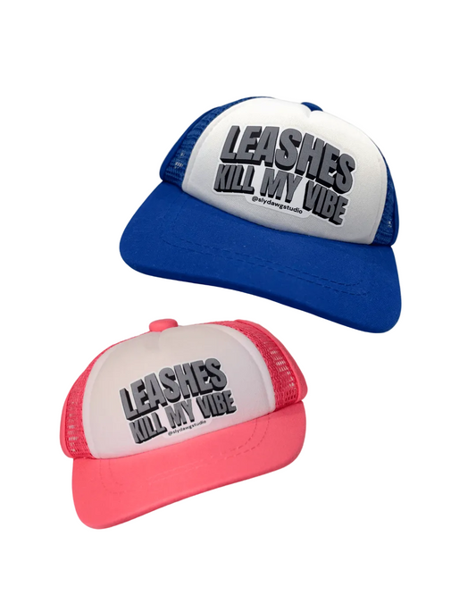 Dog trucker hat with saying detail; close-up of Leashes Kill My Vibe lettering on white foam front. Shown in blue and pink.