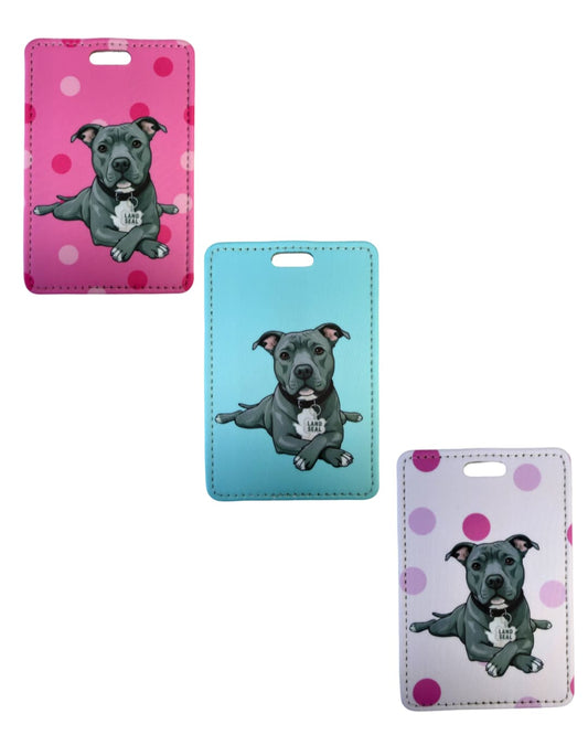 Funny pit bull luggage tag three colorways; Three faux leather luggage tags showing a grey pit bull in sploot pose with Land Seal charm, in dark pink polka dot, light blue, and light pink polka dot backgrounds.