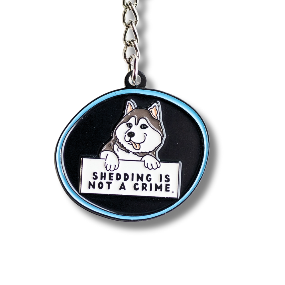 husky keychain - black with blue outline. Cartoon husky dog holding sign "shedding is not a crime" Cloe up