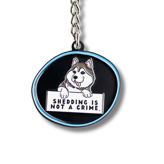 husky keychain - black with blue outline. Cartoon husky dog holding sign "shedding is not a crime" Cloe up