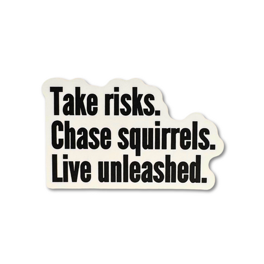 White vinyl sticker with bold black motivational text: “Take risks. Chase squirrels. Live unleashed.”