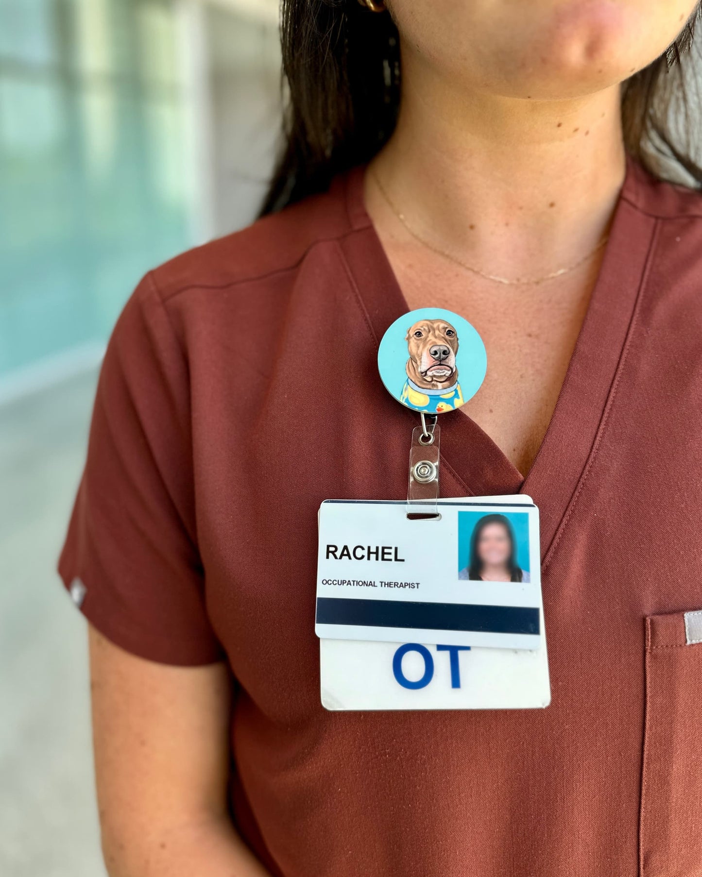Opie badge reel worn on rust scrubs by occupational therapist, pit bull illustration on blue background, retractable badge reel by Sly Dawg Studio