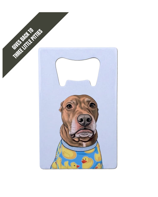 Opie Wallet Bottle Opener, white stainless steel flat bottle opener featuring Opie the pit bull in rubber duck pajamas on light gray background. Charcoal grey corner banner reads "GIVES BACKS to Three Little Pitties" in white font.