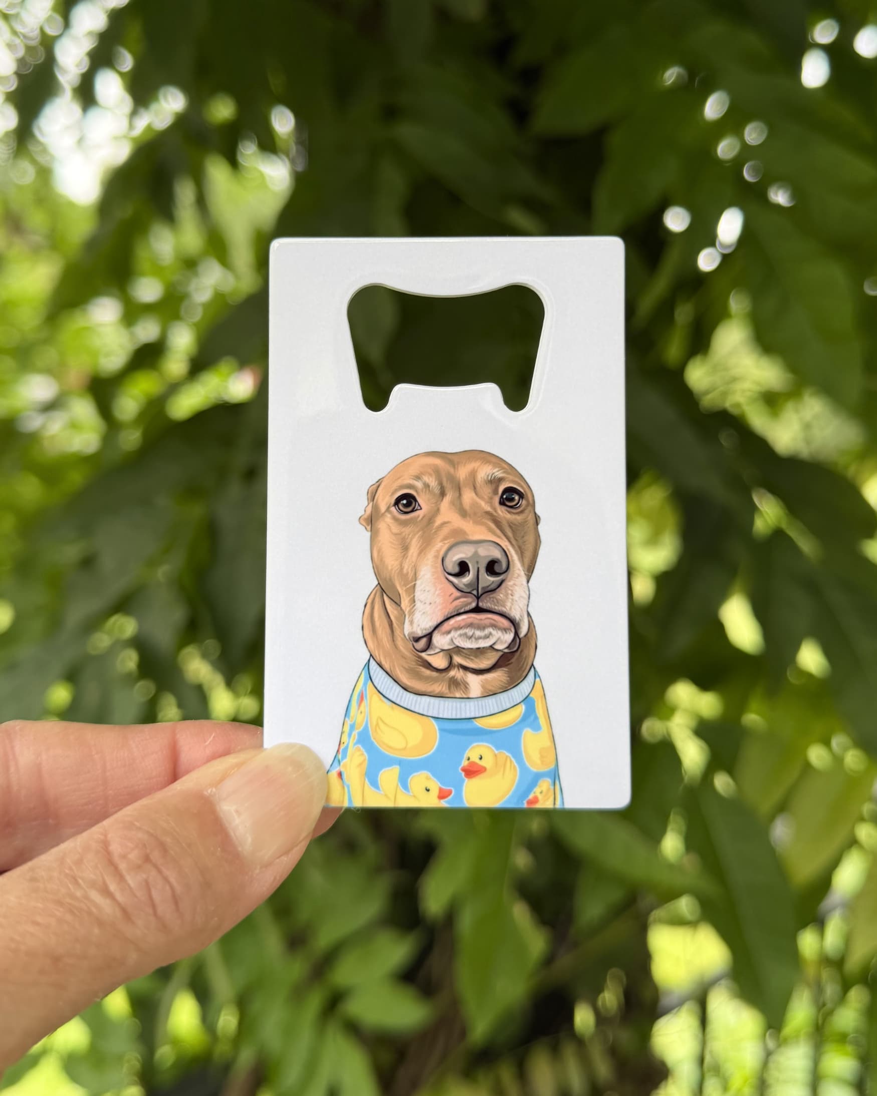 Opie Wallet Bottle Opener held outdoors against green foliage showing rubber duck pajama Opie design
