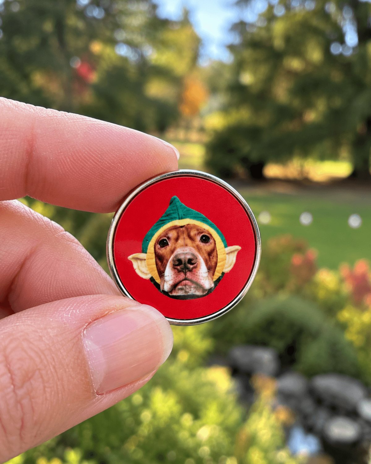 Hand holding the Opie Christmas elf lapel pin to show its 1 inch size