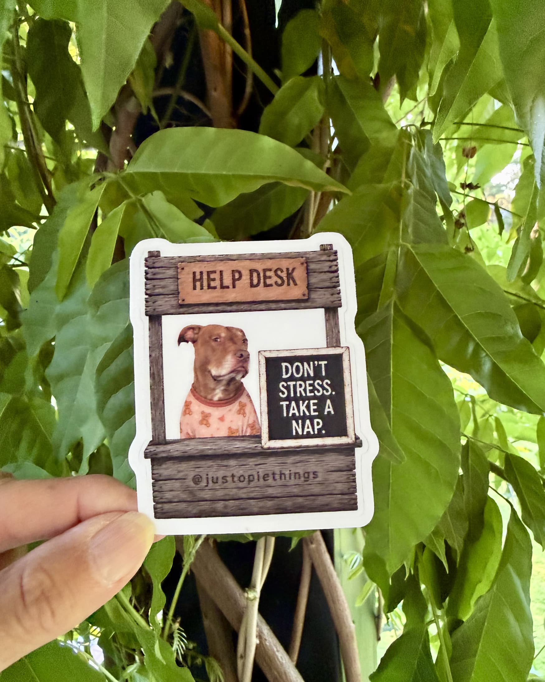 Opie Help Desk stickers, Sounds Like a Tomorrow Problem design held up outdoors against green tropical leaves