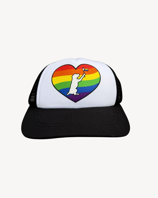 Rainbow dog hat; black and white dog trucker hat with rainbow heart and dog waving pride flag, front view on white background.