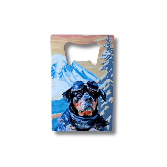 Rottweiler bottle opener with mountain artwork, featuring a dog wearing goggles against an alpine outdoor landscape, flat stainless steel wallet-size design