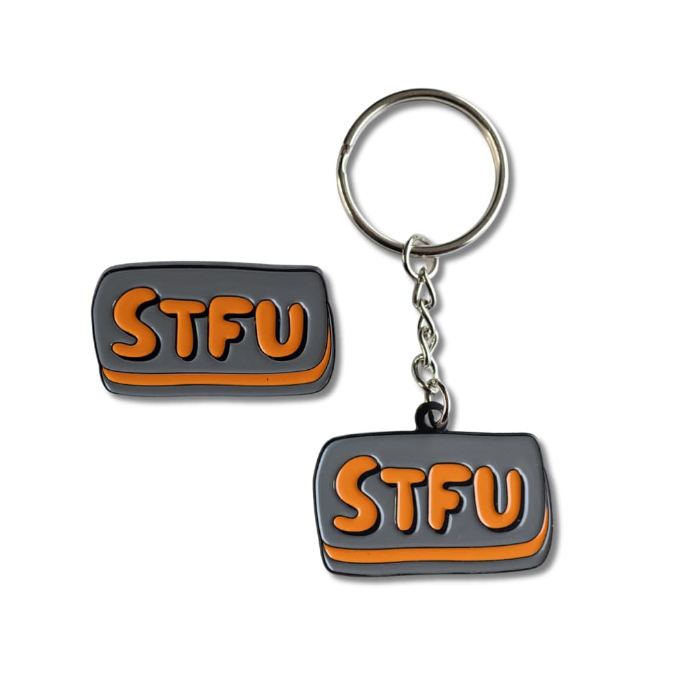 A 1.57-inch grey and orange rectangular enamel pin and matching keychain that say STFU in bold bubbly letters, representing a rude keychain and pin bundle for sarcastic gift giving.