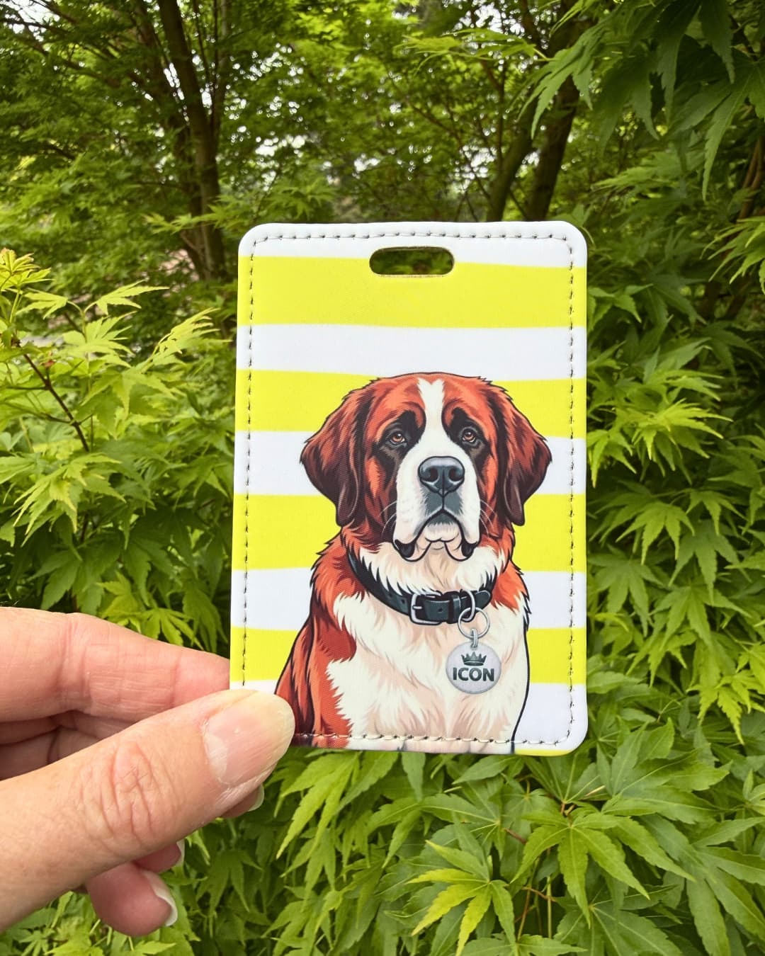 Saint bernard luggage tag handheld lifestyle shot showing Saint Bernard dog with ICON collar tag on yellow and white striped faux leather tag