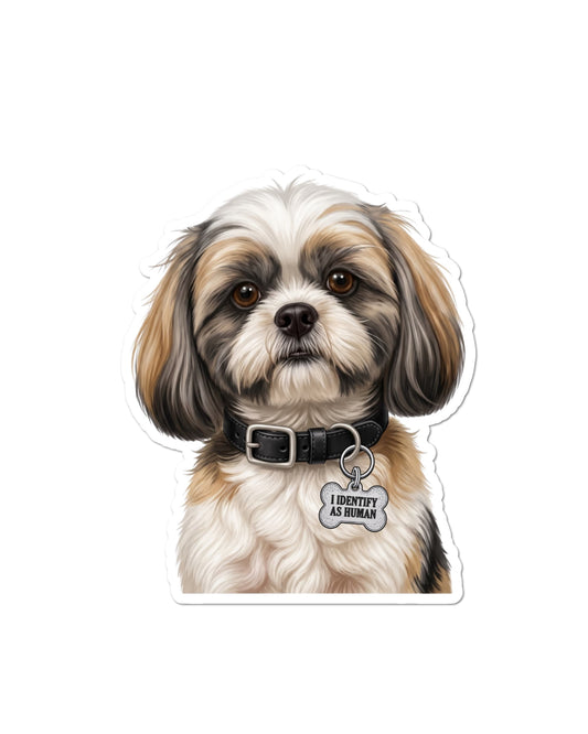  Shih Tzu sticker featuring a white, tan and charcoal gray dog with floppy ears and brown eyes, wearing a black collar with a silver bone-shaped charm reading “I IDENTIFY AS HUMAN,” on white.