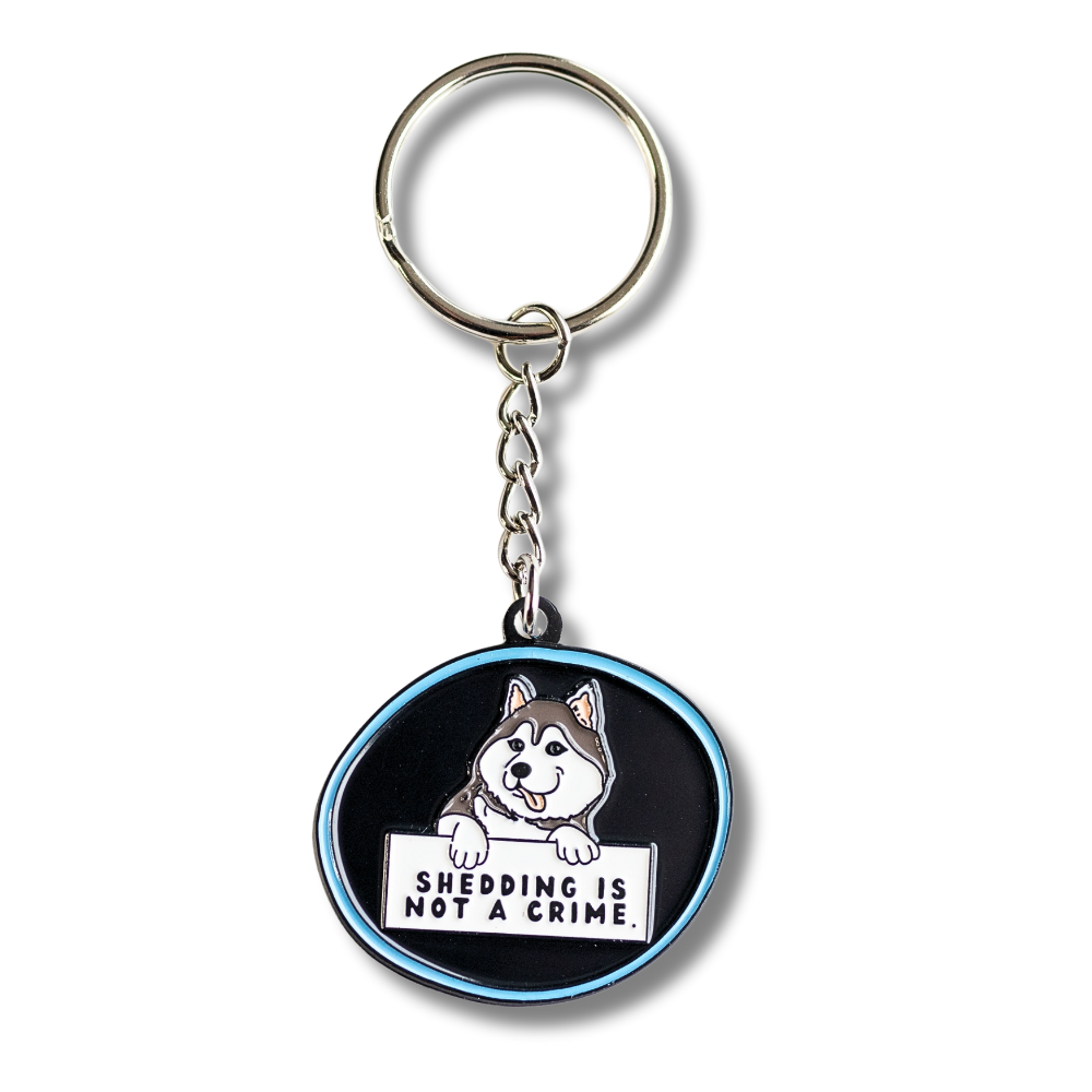husky keychain - black with blue outline. Cartoon husky dog holding sign "shedding is not a crime" Full view