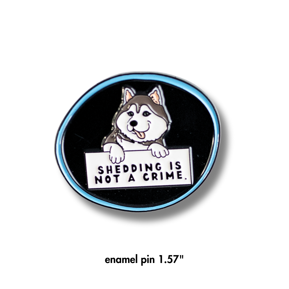 husky enamel pin - black with blue outline. Cartoon husky dog holding sign "shedding is not a crime"