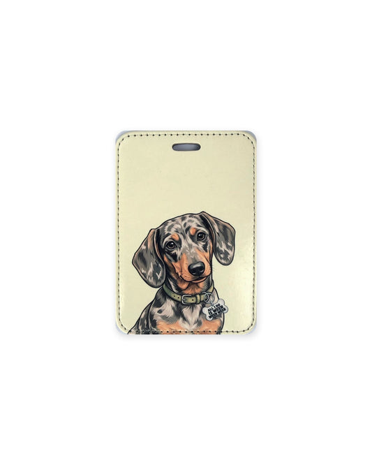 Silver dapple dachshund luggage tag with an original design of a doxie wearing a sage green collar and a bone-shaped charm that reads "All I Do Is Ween Ween Ween", on a tan background. Faux leather luggage tag with stitched edges and a slot at the top.