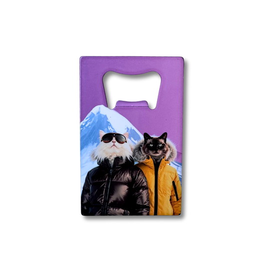 Adventure cat bottle opener gift for skiers; snowy mtn and pink purple background. two sassy cats wearing puffer coats.