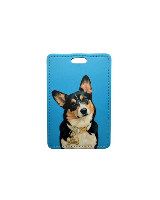 tri color corgi luggage tag flat lay showing black tan and white pembroke welsh corgi with NOSY NEIGHBOR bone tag on solid blue faux leather travel tag