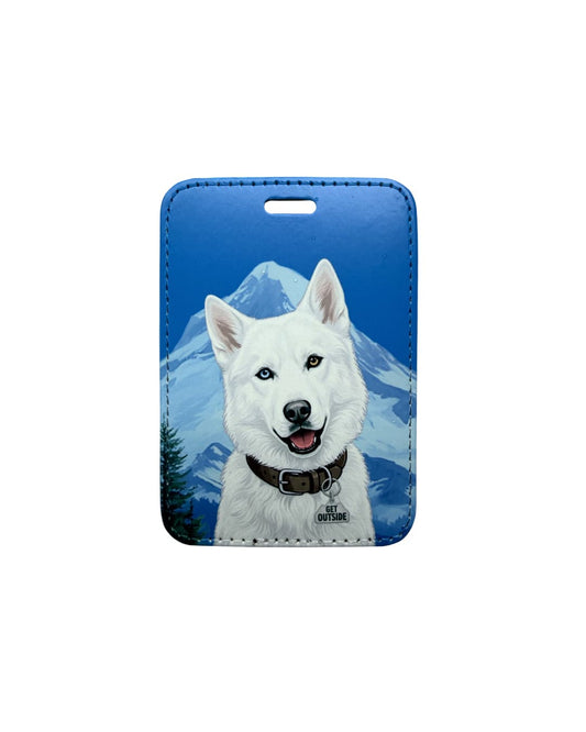 White husky dog luggage tag; Fun faux leather luggage tag featuring a pure white Siberian Husky with one blue eye and one brown eye, dark brown collar with Get Outside charm, vivid blue sky and snow-capped mountain background.